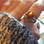 Eco silver round ring band with an Amber gemstone. It's complemented by a wishbone wring wrapped around the bottom of the gemstone.