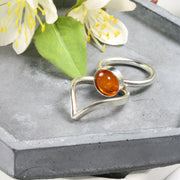 Eco silver round ring band with an Amber gemstone. It's complemented by a wishbone wring to wrap around the bottom of the gemstone.