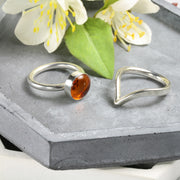 Eco silver round ring band with an Amber gemstone. It's complemented by a wishbone wring to wrap around the bottom of the gemstone.