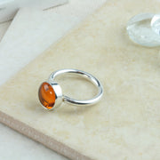 Eco silver round ring band with an Amber gemstone. It's complemented by a wishbone wring wrapped around the bottom of the gemstone.
