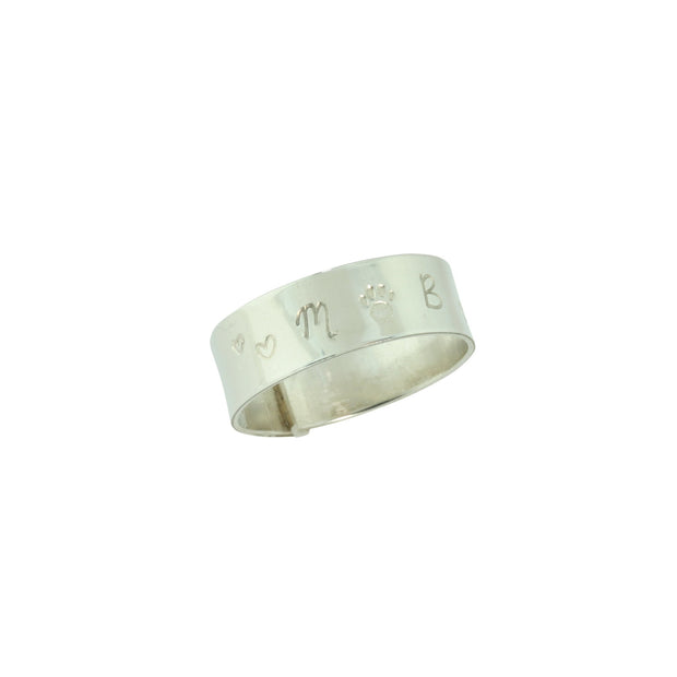 Personalised silver wrap ring. The ring is made from eco silver and 7mm wide. This ring is personalised with some hearts and a paw, with the letters M and B on either side. The ring is left oen and is adjustable, making it comfortable whether it&