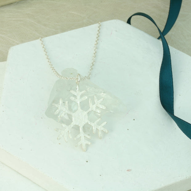 Silver pendant necklace featuring a snowflake with a hexagon in the heart. It has a hammered shiny finish which sparkles when it catches the light. The chain can be fastened at two different lengths making it versatile to match with any outfit.