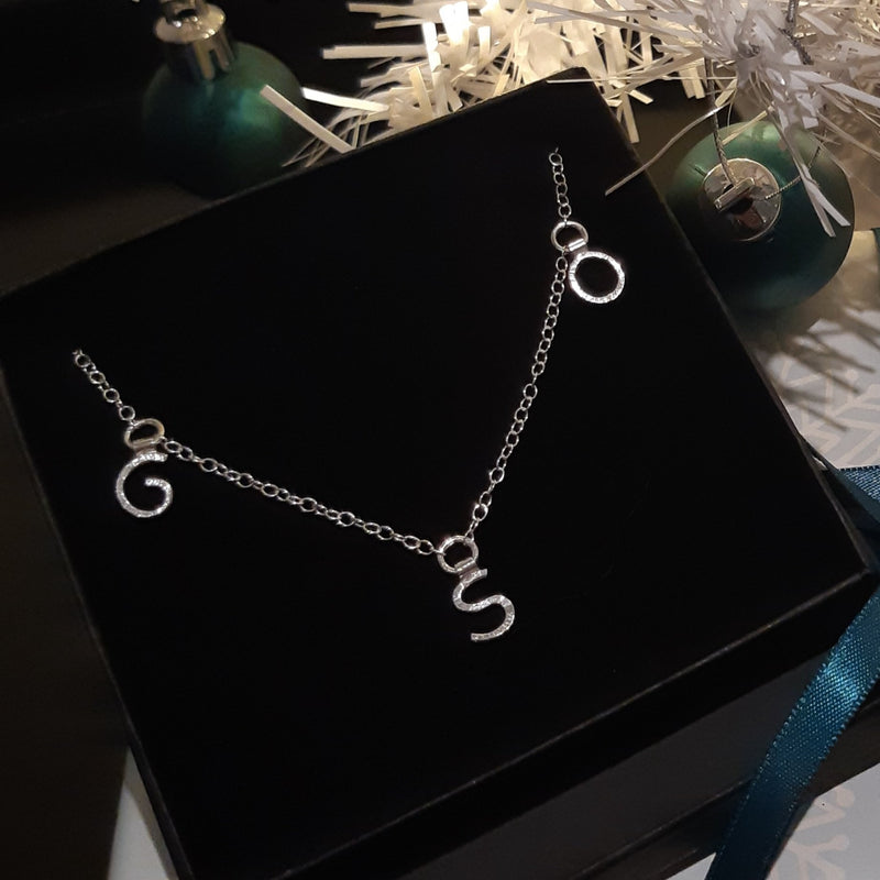 Silver necklace featuring three letters. The necklace is 46cm long.