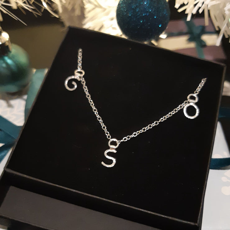 Silver necklace featuring three letters. The necklace is 46cm long.