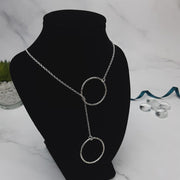 Silver y necklace featuring a hoop at either end of the chain. The hoops have been flattened and given a hammered texture and shiny finish. The chain loops through one of the hoops. By pulling the lower hoop you can adjust how high or low it sits.