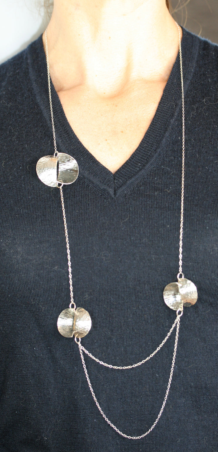 Silver statement opera necklace with 3 split circles, the two lower split circles are connected by two chains creating a drop effect. The  circles are split in half and domed, then soldered together in opposite directions. Both sides have a different hammered texture, one half has a shiny mirror finish, the other an oxidised buffed finish.