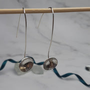 Eco silver drop cup earrings with 9ct gold ball. The drop hook and cup are made from eco silver. The cup has been given a stripe texture and a mirror finish. The gold ball sits in the bottom half of the cup.