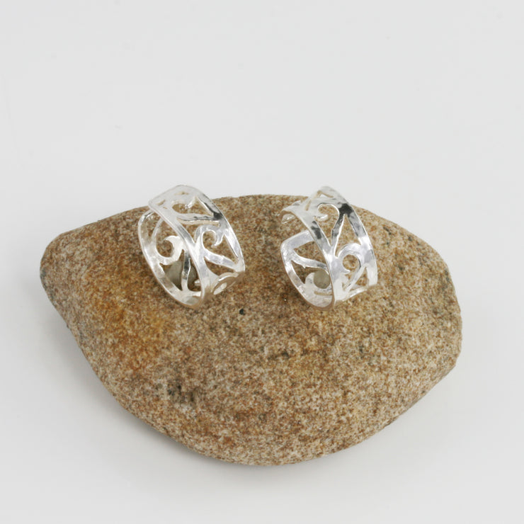 Eco silver ear cuffs featuring 5 half heart shaped swirls. The half hearts sit inside an open band and are lined up one after the other in a perfect line. They have a hammered shiny finish.