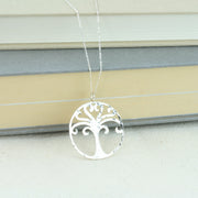 A silver round tree of life pendant necklace. A circle featuring a sawn out unique Tree of Life design. It measures 3 cm in diameter and has round curled branches with the top two branches coming together in a heart shape. It has a shiny hammered texture and the necklace is available in 45 cm and 76 cm lengths.
