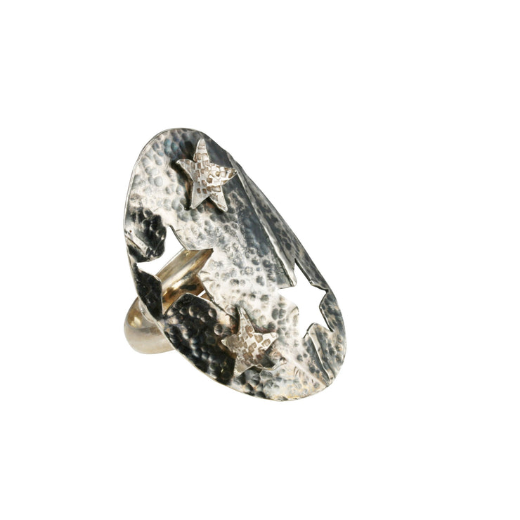 Silver ring with a large oval shape that wraps around the finger. It features two folds and a hammered texture. Two stars shapes are cut out and placed on the oval. The oval has an oxidised darker finish and the two stars have a shiny silver finish. The D shaped silver ring band is adjustable in size.