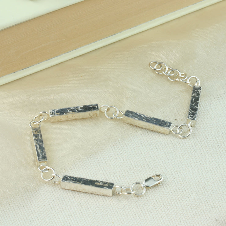 Silver bars bracelet. This bracelet features five silver bars that have been given a square hammered texture. They are connected with jump rings and it is fastened with a lobster clasp.
