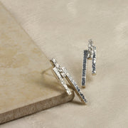 Eco silver stud earrings featuring three bars with different lenghts and textures. They have been placed at different heights.