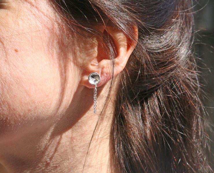 Eco silver cup chain earrings. Featuring a cup stud earing with a pebble or stripe texture that has a shiny mirror finish. They have a small 9ct gold ball sitting in the bottom half of the cup. A 40mm chain is attached to the bottom and loops around the back with the stud through it.