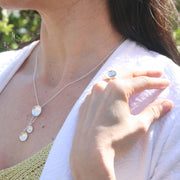 Silver cups drop necklace; a silver necklace featuring a drop pendant with a larger domed cup at the top and two smaller cups attached by chain for a drop effect. One cup is smaller than the other and features a gold ball. It has a pebble texture. Combined with the eco silver cup ring.