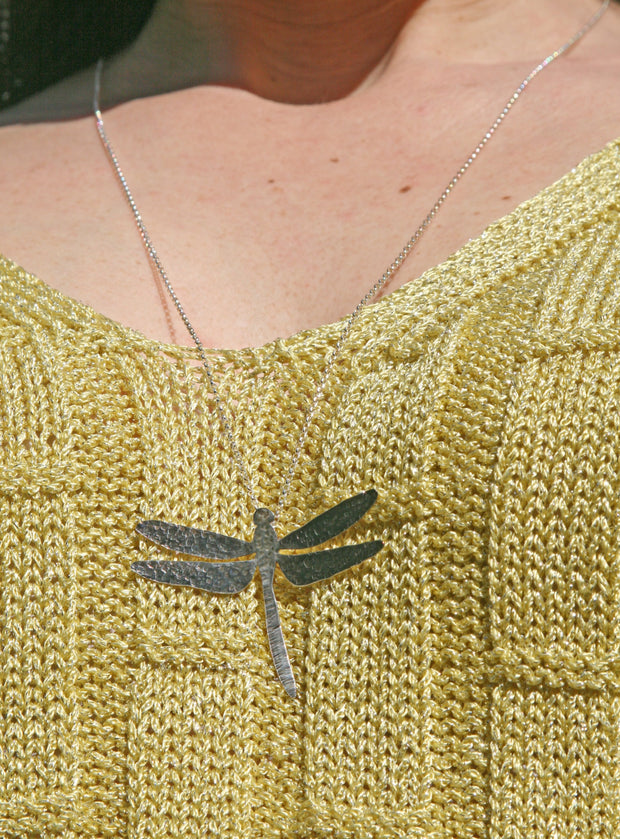 Pendant necklace featuring a pendant in the shape of a dragonfly. It has been given a hammered texture with the wings given an oxidised darker finish.