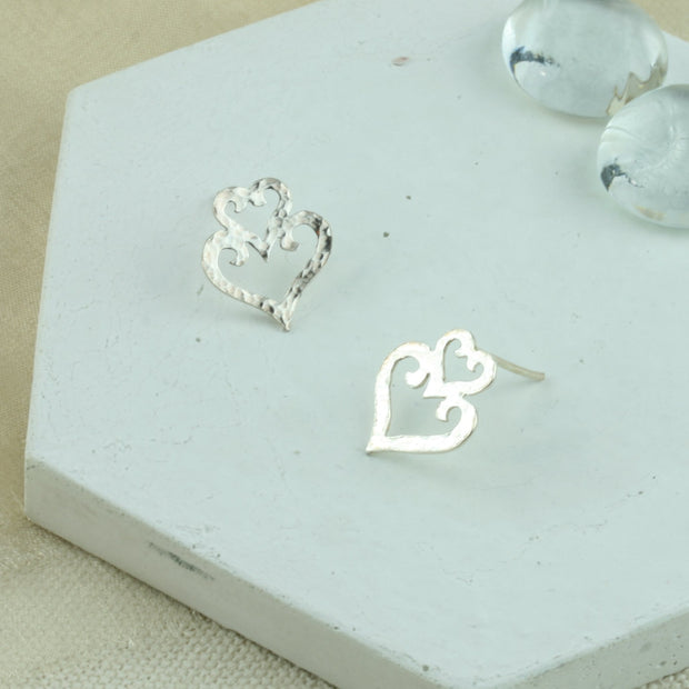 Eco silver heart stud earrings. They have a hammered texture and shiny polished finish.