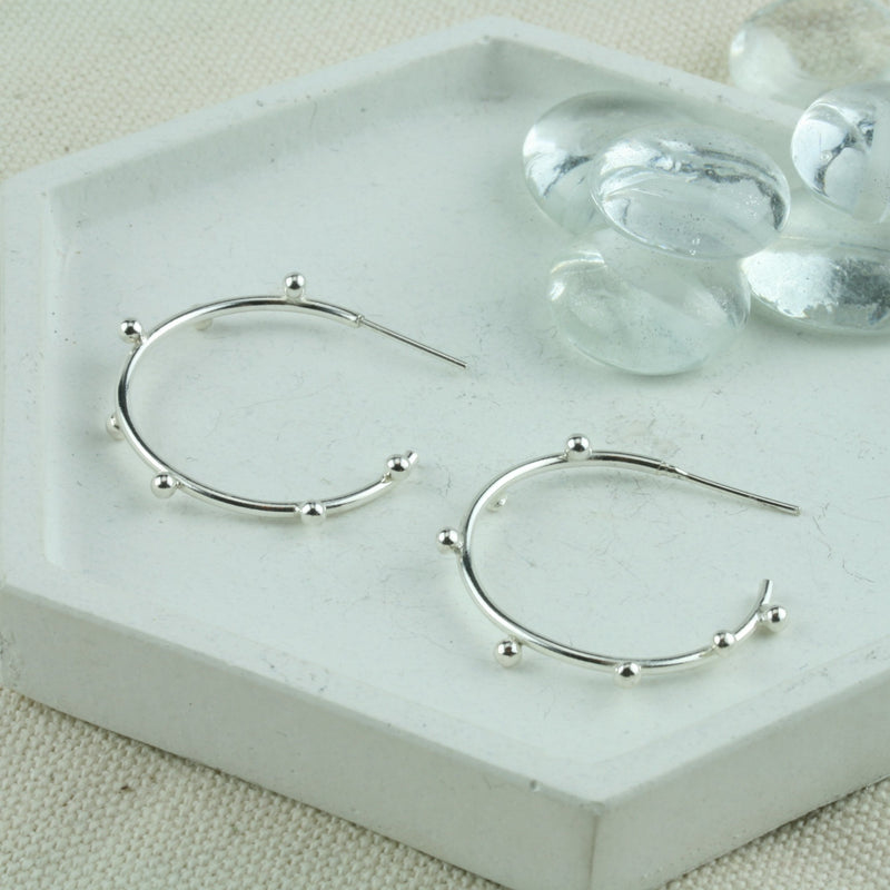 Large silver hoop earrings with 7 silver balls on each hoop. They&