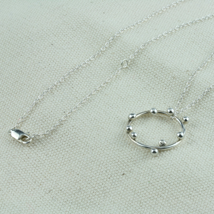Silver hoop pendant featuring 9 silver balls. This is a handmade pendant, made form eco-silver. The trace chain necklace can be fastened with its lobster clasp at either 45cm or 50cm.
