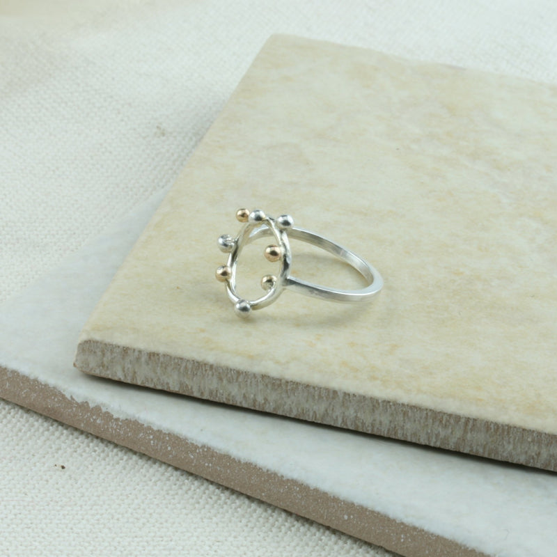 Eco silver ring featuring a square ring band and a round hoop. The hoop features 4 silver and 4 9ct gold balls spread around. It has a shiny mirror finish.