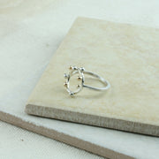 Eco silver ring featuring a square ring band and a round hoop. The hoop features 4 silver and 4 9ct gold balls spread around. It has a shiny mirror finish.