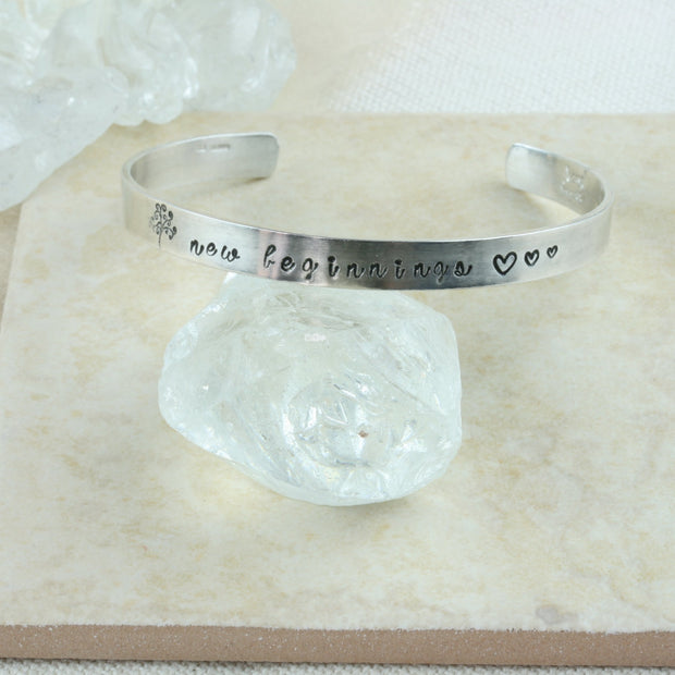 Silver personalised bangle. This bangle bracelet features a Tree of life stamp and three hearts with &