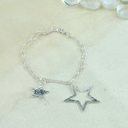 Silver bracelet featuring two stars made from eco silver. They both have a mirror finish at the back and a hammered finish at the front. The larger star has a striped texture and smaller star that has been sawn out of the larger star has a round texture at the front. The two figaro chains are the perfect finish to this shiny bracelet.