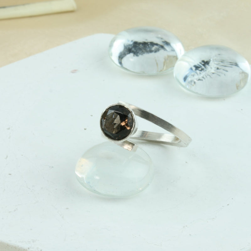 Eco silver twisted ring with Smoky Quartz gemstone. A square ring band twisted to sit comfortably around the finger and hold the gemstone. The setting is a collet setting which holds the gemstone in place about 10mm higher above the ring band.