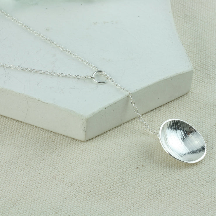 Eco silver cup y necklace. A domed and texture cup is attached at the end of the chain. The chain feeds through a jump ring attached to the other end of the chain, so it slides through and can be adjustable in length.