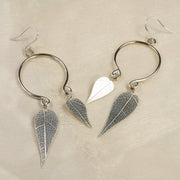 Eco silver hoop earrings with two leaves. These hoops have been shaped into two loops at the bottom rather than being closed. Both loops feature a leaf different in size. The leaves were given a real leaf texture at the front and a mirror finish at the back. Dangling from a hook earring these earrings capture the light to make them sparkle and shine.