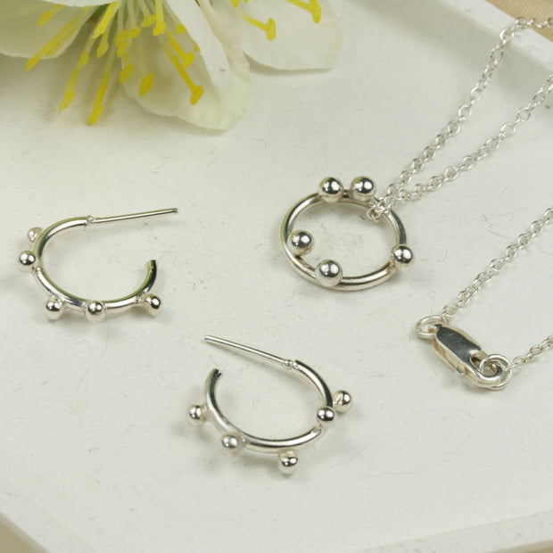 A set with a silver hoop pendant necklace and silver hoop earrings with 5 silver balls. The pendant is made from eco silver and the necklace can be fastened at two different lengths with a lobster clasp.