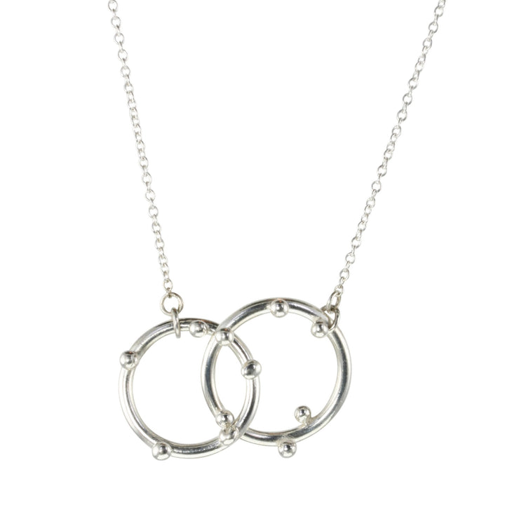 Silver necklace featuring two hoops, one larger and one smaller hoop. With 5 silver balls on the smaller hoop and 6 silver balls on the larger hoop. The silver trace chain is attached to both hoops and fastens with a lobster clasp. The necklace is 45 cm / 18" long.