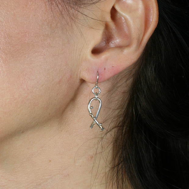 Silver hook earrings featuring a twirl shape. Three 9ct gold and three silver balls are featured to one side at the front of the earrings. They have a shiny mirror finish.
