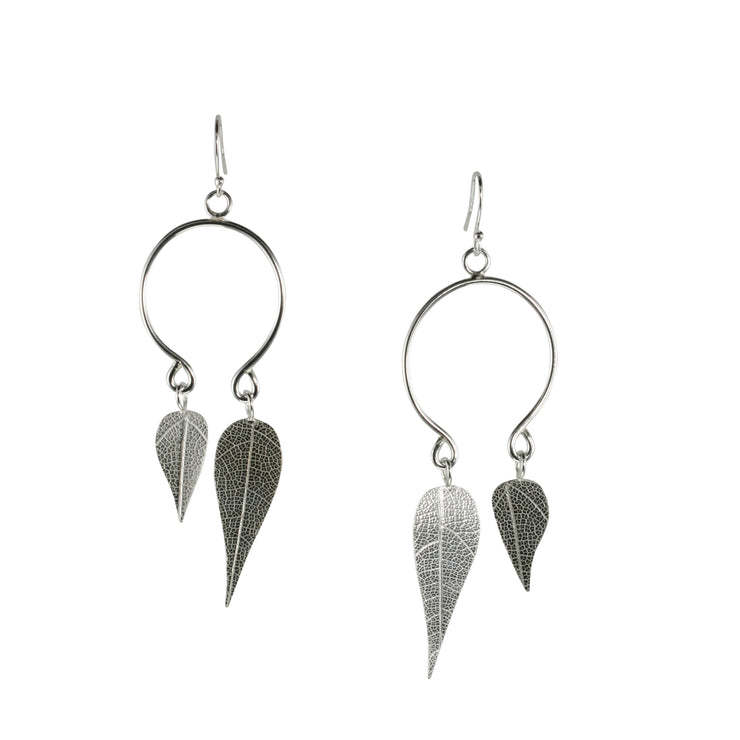 Eco silver hoop earrings with two leaves. These hoops have been shaped into two loops at the bottom rather than being closed. Both loops feature a leaf different in size. The leaves were given a real leaf texture at the front and a mirror finish at the back. Dangling from a hook earring these earrings capture the light to make them sparkle and shine.