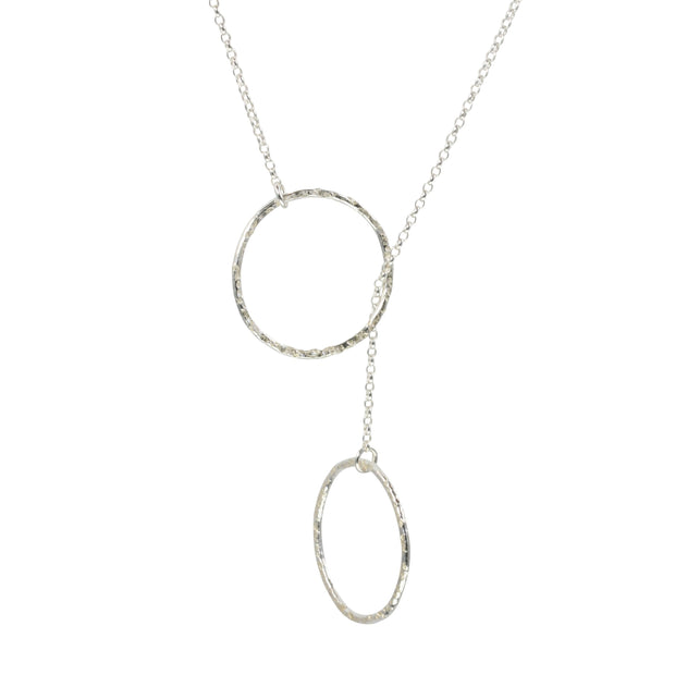 Silver y necklace featuring a hoop at either end of the chain. The hoops have been flattened and given a hammered texture and shiny finish. The chain loops through one of the hoops. By pulling the lower hoop you can adjust how high or low it sits.