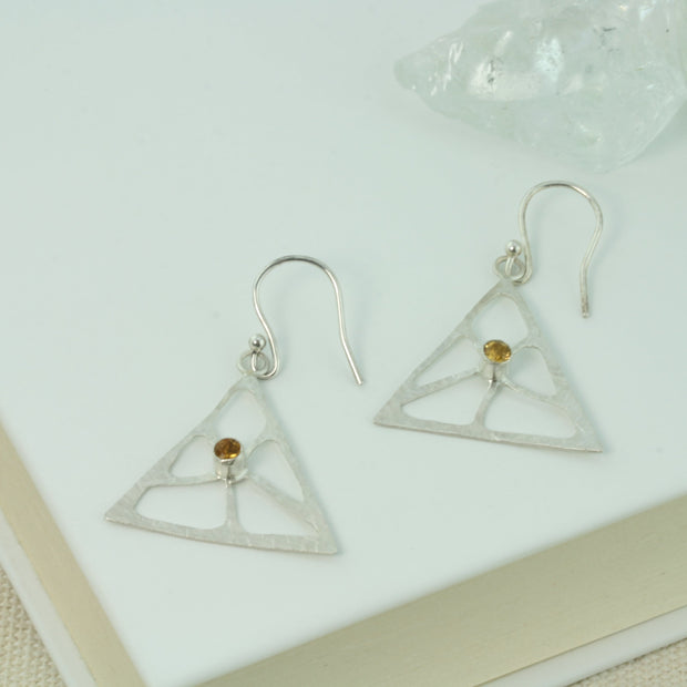 Silver triangle earrings featuring a psychedelic flower shape which has ben sawn out by hand. The heart of the flower features a Citrine gemstone in a tube setting. The silver has a hammered texture and a shiny finish.