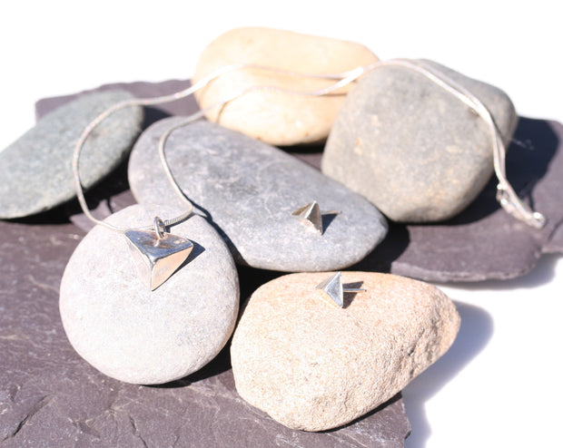 A silver pendant in the shape of a pyramid.