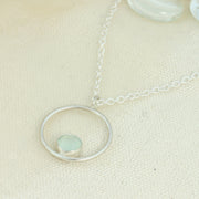 Silver pendant necklace featuring a hoop with a gemstone in inside at the bottom. The gemstone measures 8mm in diameter. This pendant features an Aqua Blue Chalcedony Rose cut cabochon gemstone, other options are available.
