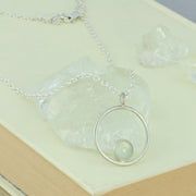 Silver pendant necklace featuring a hoop with a gemstone in inside at the bottom. The gemstone measures 8mm in diameter. This pendant features an Aqua Blue Chalcedony Rose cut cabochon gemstone, other options are available.