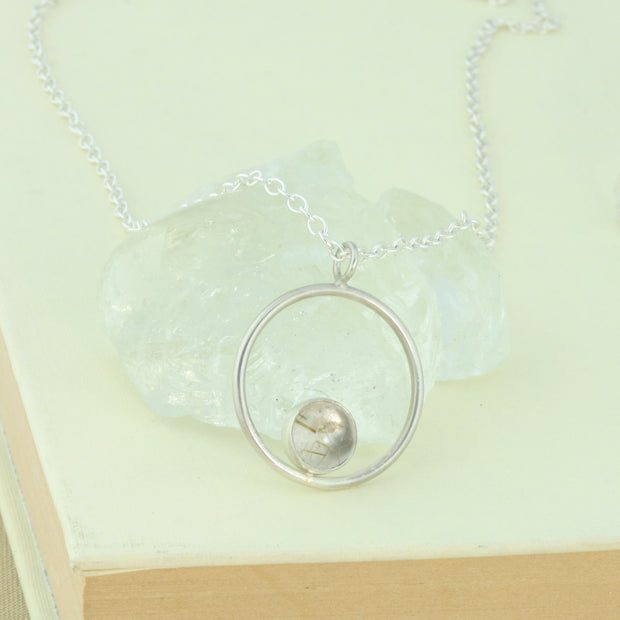 Silver pendant necklace featuring a hoop with a gemstone in inside at the bottom. The gemstone measures 8mm in diameter. This pendant features a Golden Rutile Quartz cabochon gemstone, other options are available.