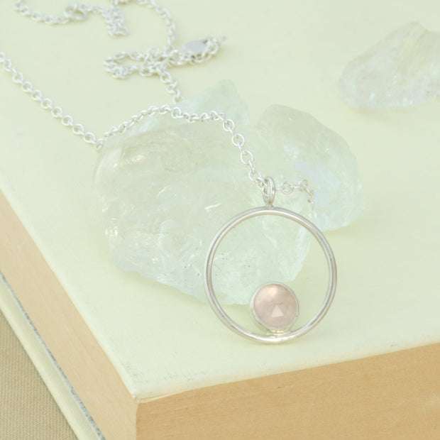 Silver pendant necklace featuring a hoop with a gemstone in inside at the bottom. The gemstone measures 8mm in diameter. This pendant features an Rose Quartz Rose cut cabochon gemstone, other options are available.