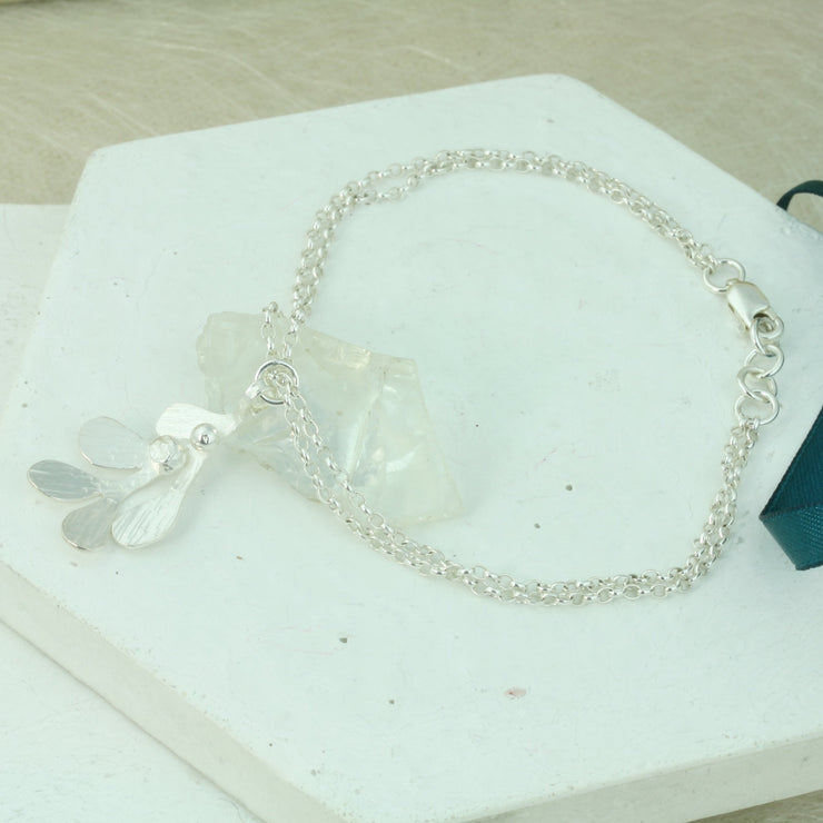 Silver chain bracelets, made with two strands of trace chain and featuring a Mistletoe charm. The charm has five leaves with a hammered shiny textured finish and two silver balls as berries. 