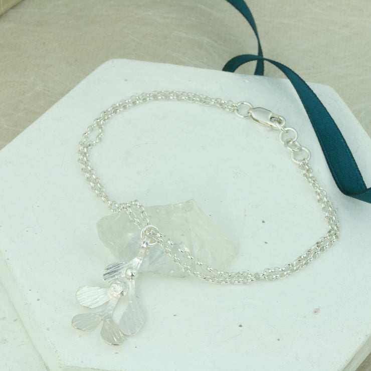 Silver chain bracelets, made with two strands of trace chain and featuring a Mistletoe charm. The charm has five leaves with a hammered shiny textured finish and two silver balls as berries. 