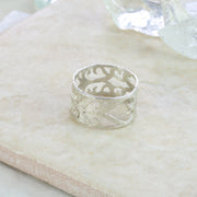 Silver Tree of Life ring band. The band is 10mm wide and features a unique Tree of Life design over the full length of the ring band. It has a hammered texture and a shiny finish.