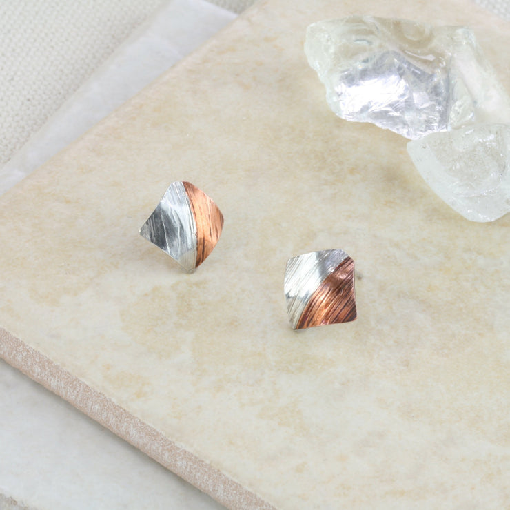 Square stud earrings, half in copper and the other half in silver. They have a round mirror finish and come in a stripe hammered mirror finish too. They&