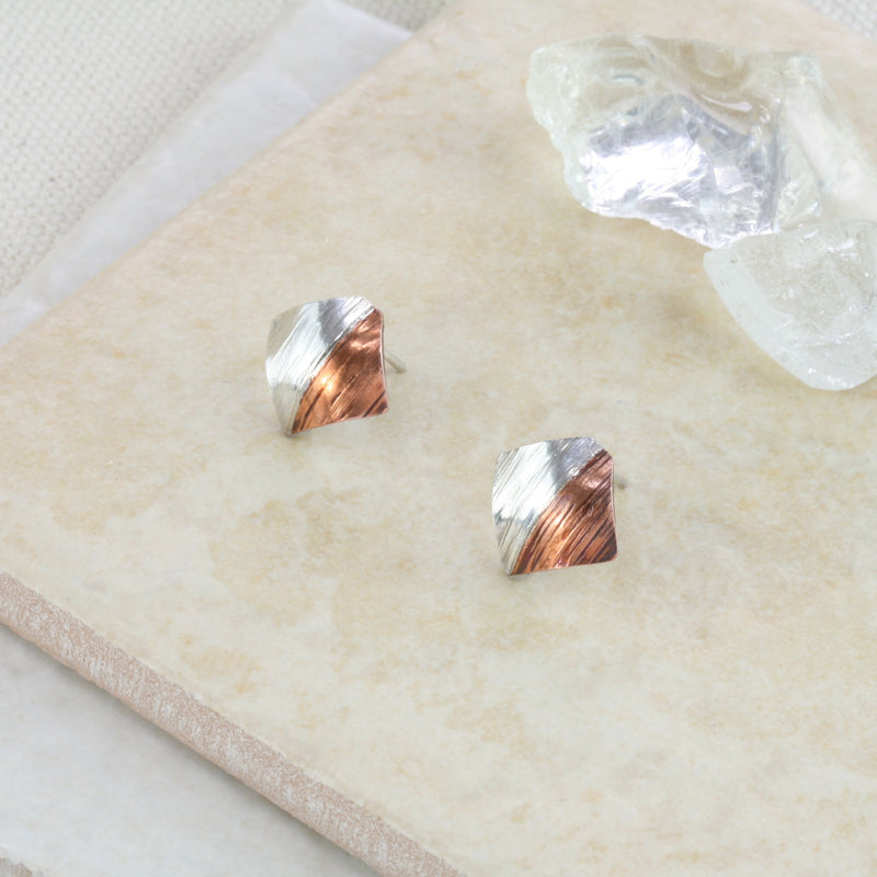 Square stud earrings, half in copper and the other half in silver. They have a round mirror finish and come in a stripe hammered mirror finish too. They&