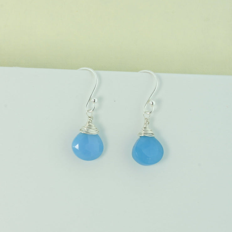 Silver briolette earrings featuring Blue Chalcedony faceted heart gemstones. The facets point at different angles catching the light perfectly for a bit shimmer and shine. They are wrapped with eco silver wire and dangle from silver earrings hooks.