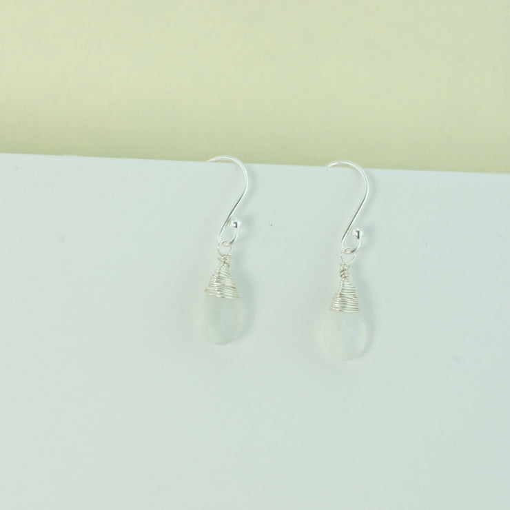 Silver briolette earrings featuring White Moonstone faceted teardrop gemstones. The facets point at different angles catching the light perfectly for a bit shimmer and shine. They are wrapped with eco silver wire and dangle from silver earrings hooks.