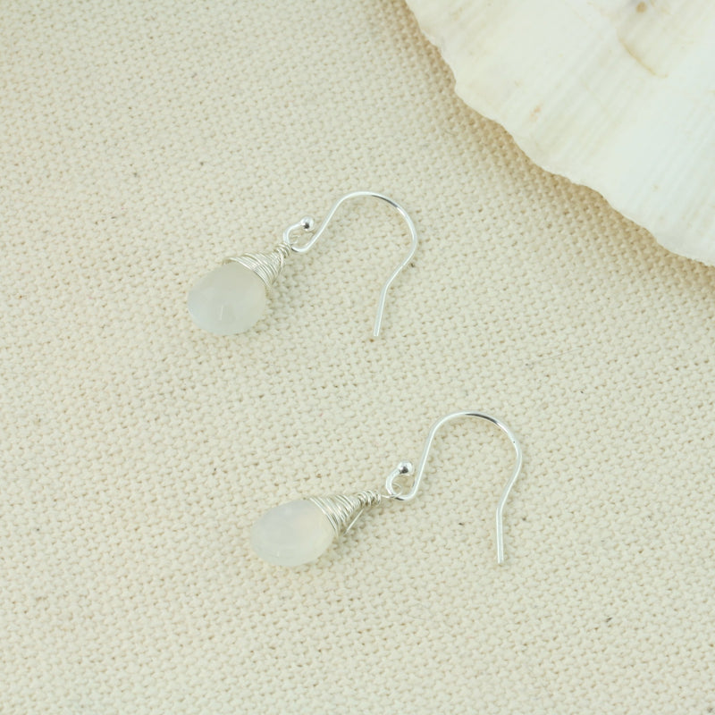 Silver briolette earrings featuring White Moonstone faceted teardrop gemstones. The facets point at different angles catching the light perfectly for a bit shimmer and shine. They are wrapped with eco silver wire and dangle from silver earrings hooks.