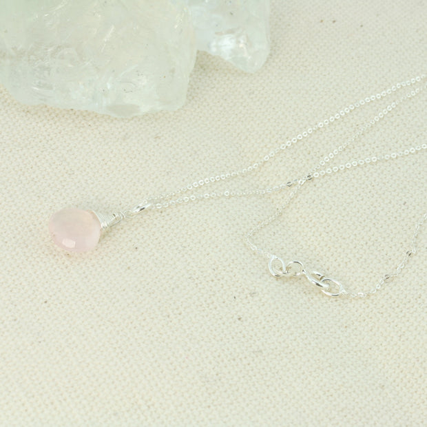 Silver briolette pendant necklace featuring a Rose Quartz faceted teardrop gemstone. The facets point at different angles catching the light perfectly for a bit shimmer and shine. It is wrapped with eco silver wire and dangles from a delicate silver necklace.