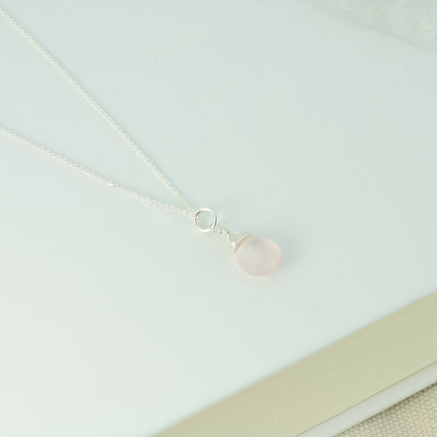 Silver briolette pendant necklace featuring a Rose Quartz faceted teardrop gemstone. The facets point at different angles catching the light perfectly for a bit shimmer and shine. It is wrapped with eco silver wire and dangles from a delicate silver necklace.